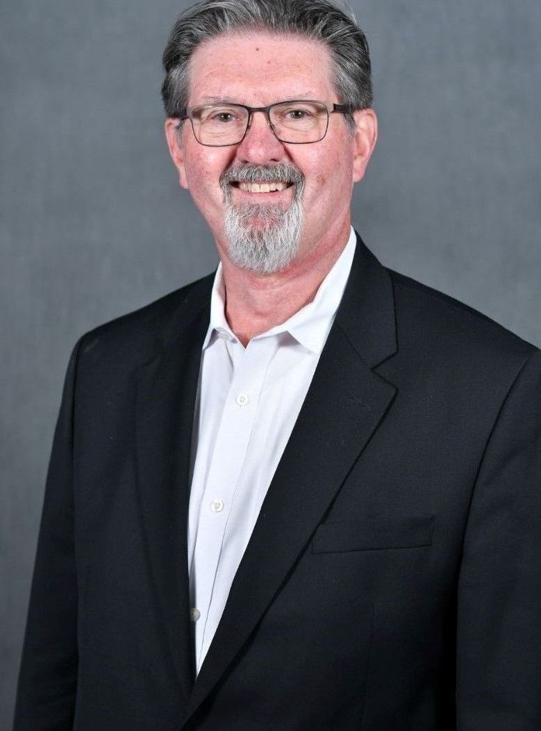 A man in a suit and glasses is smiling for the camera