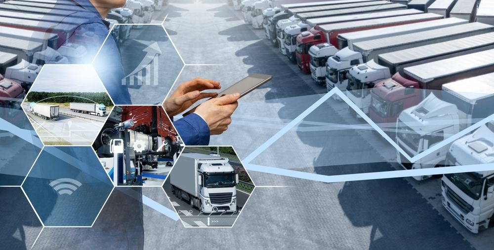 Hand holding a smartphone over a digital logistics dashboard with trucks, warehouses, and transport routes