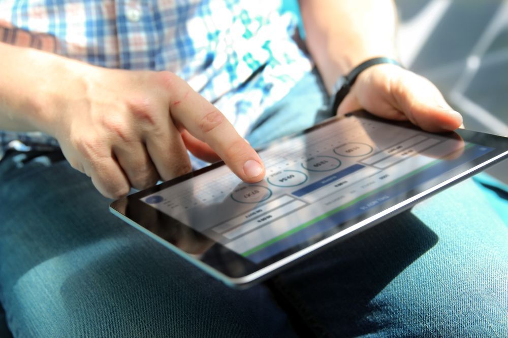 Person using a tablet with a touchscreen interface while sitting on a couch