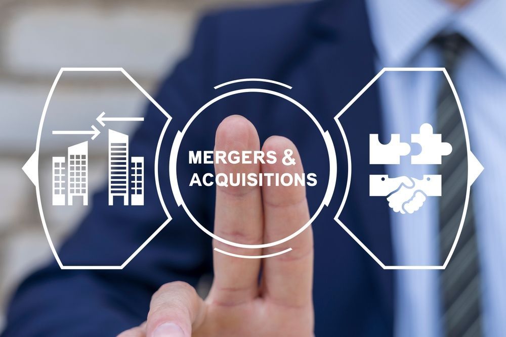 Businessman touching digital interface labeled “Mergers & Acquisitions” with growth and puzzle icons