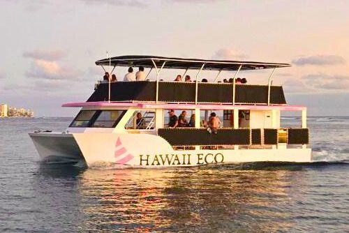 White-and-pink boat named Celebration cruising on blue water with mountains in the background