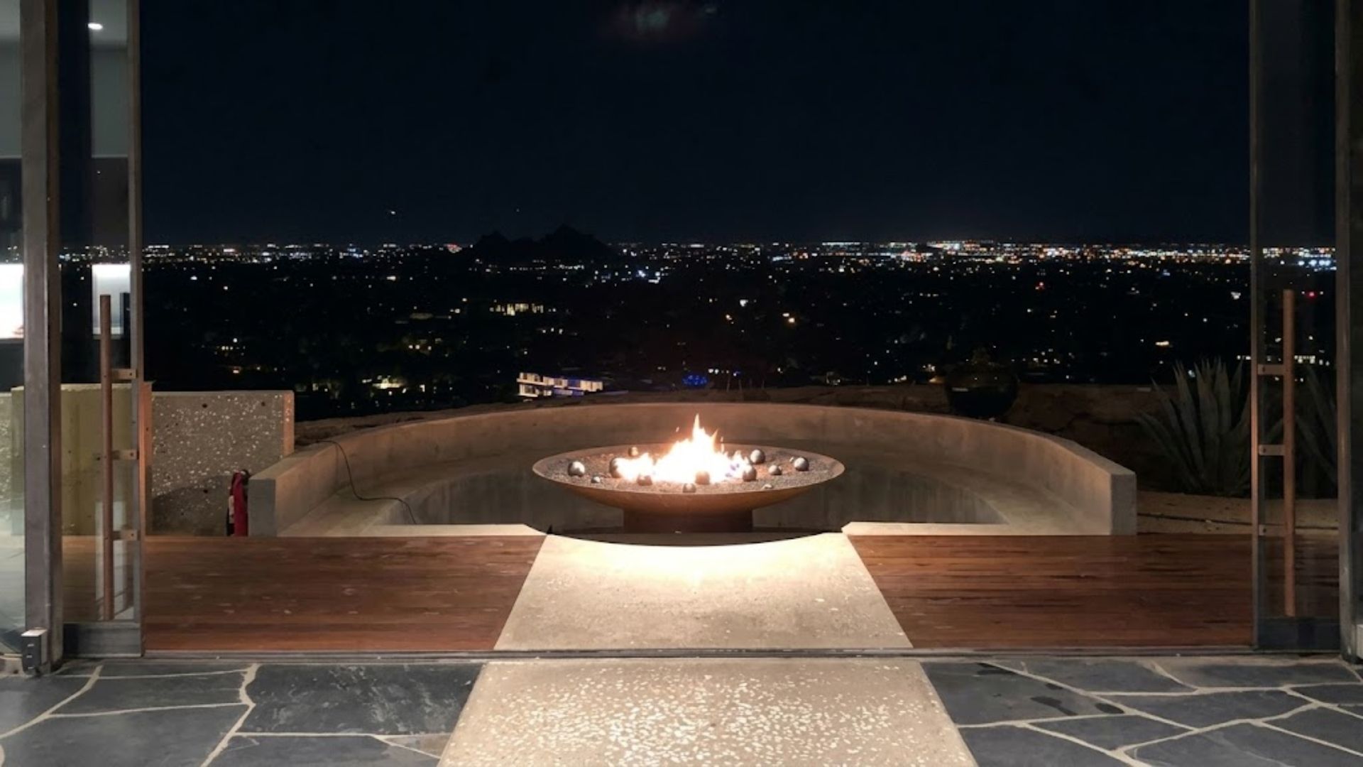 Modern patio with a circular fire pit overlooking city lights at night