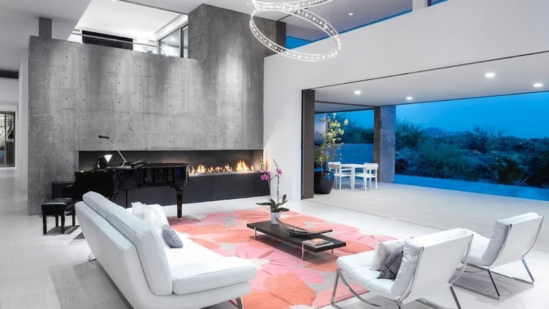 Modern living room with white sofas, black fireplace, and floor-to-ceiling windows overlooking blue water.