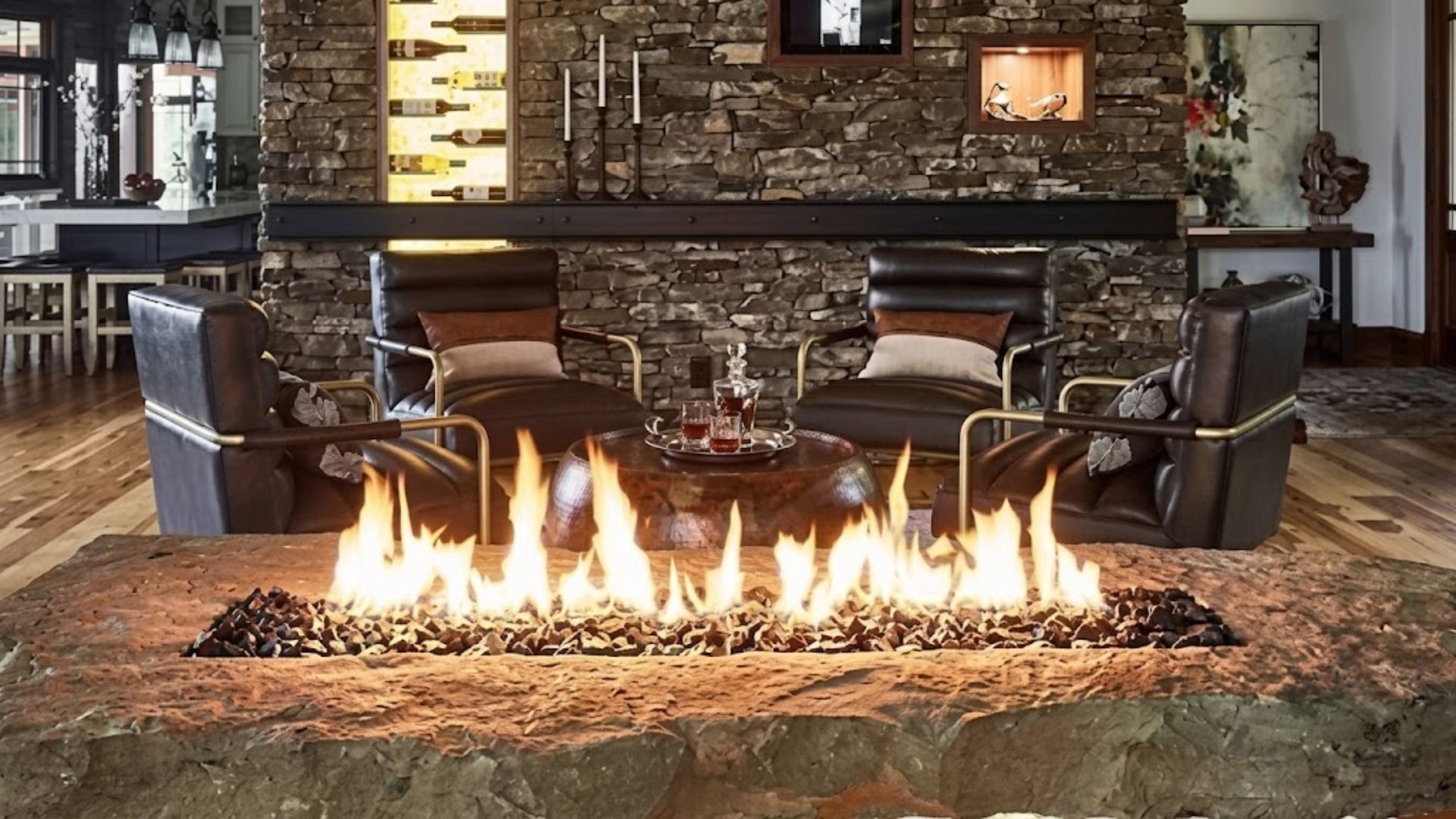 Stone fireplace with a row of flames in a rustic lounge, surrounded by leather chairs and a bar backdrop