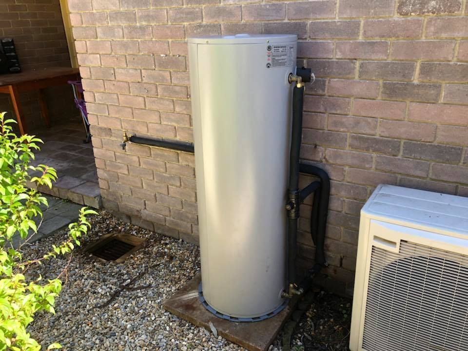 Water heater tank next to a brick wall and air conditioning unit outside. — Precise Plumbing & Drainage In Conder, ACT