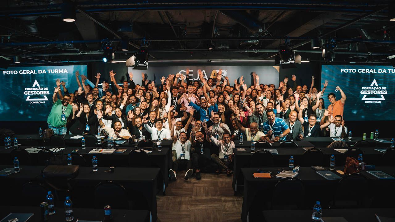 Grande grupo de pessoas em um evento, braços levantados em comemoração, em