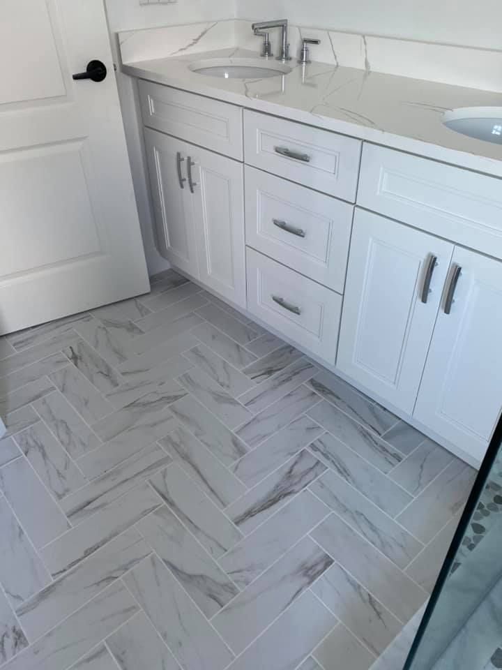 White bathroom vanity with sink, drawers, cabinets, and light gray patterned tile floor