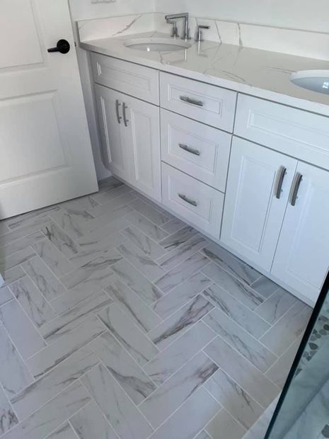 White bathroom vanity with sink, drawers, cabinets, and light gray patterned tile floor