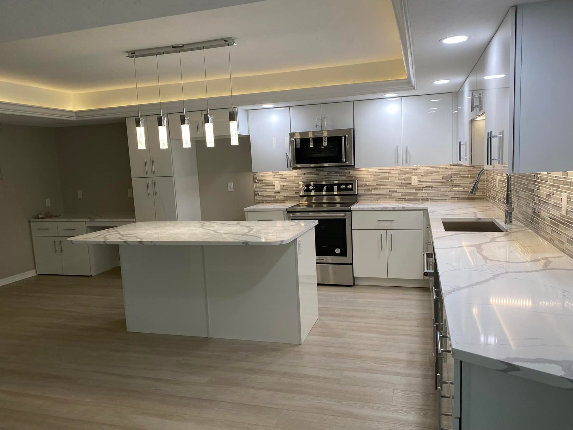 Modern white kitchen with island, pendant lights, and stainless steel appliances