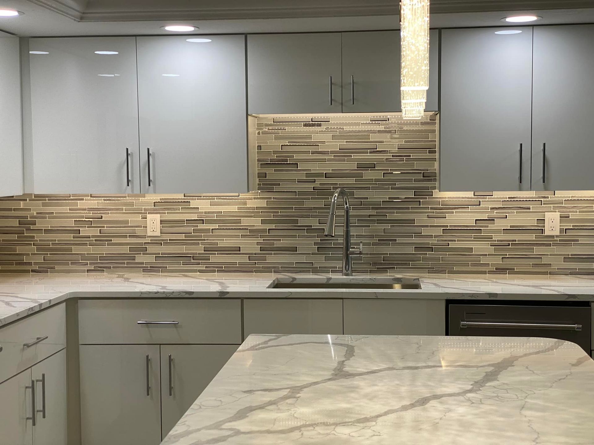 Modern kitchen with gray cabinets, mosaic tile backsplash, and marble-look island countertop