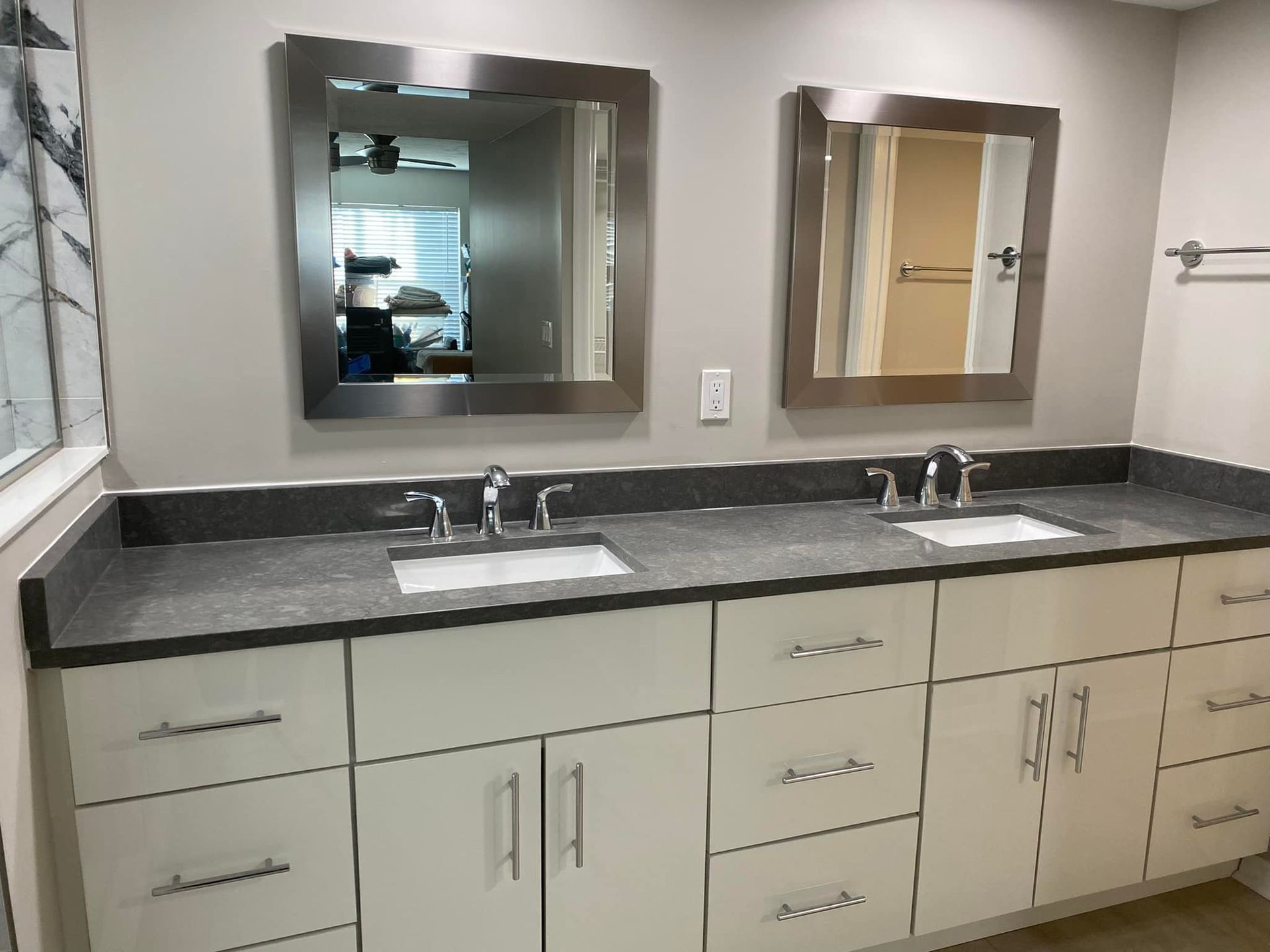 Modern bathroom vanity with two mirrors, double sinks, and dark countertops