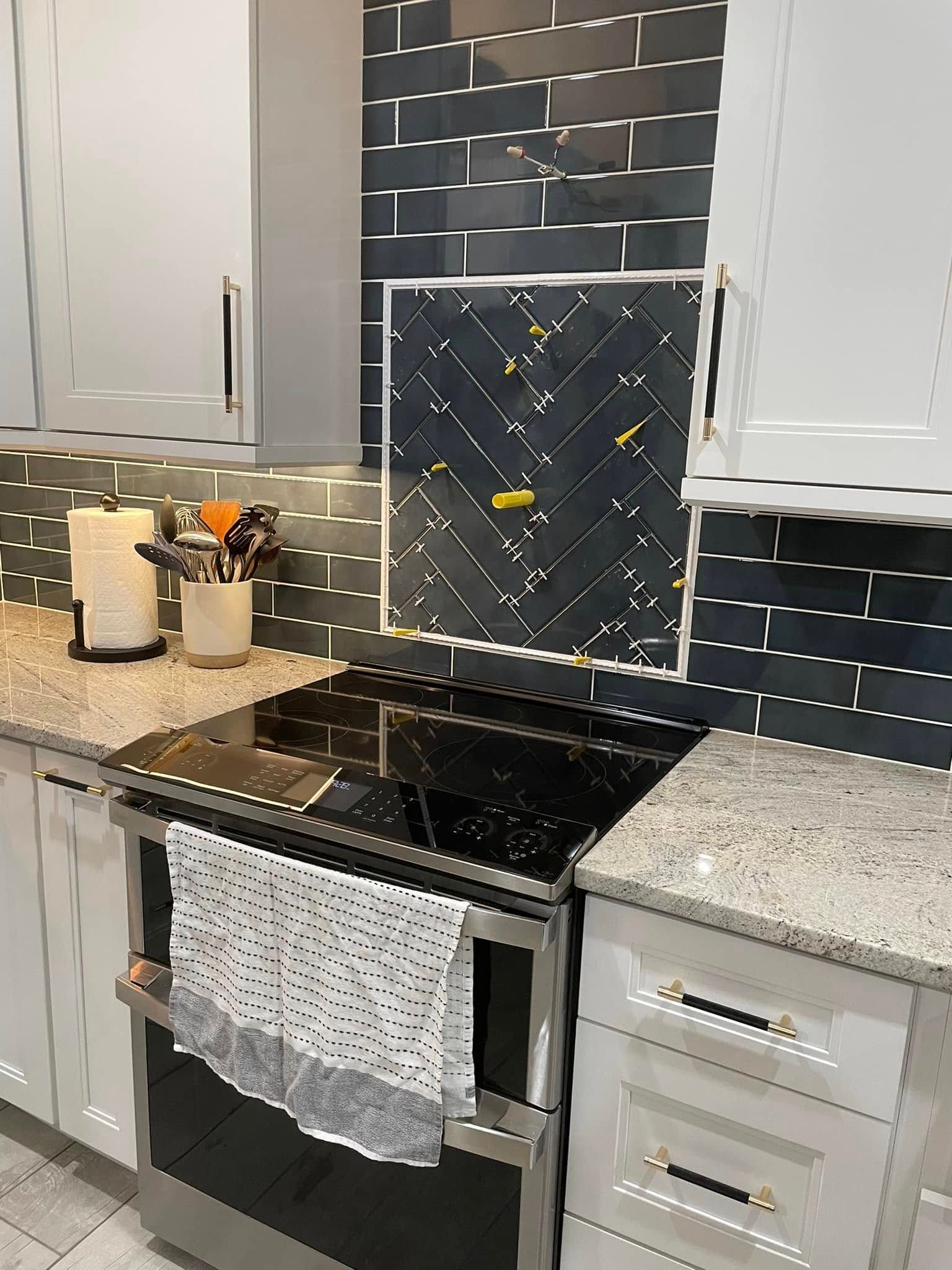 Modern kitchen with black subway tile backsplash, stainless stove, granite counters, and light cabinets
