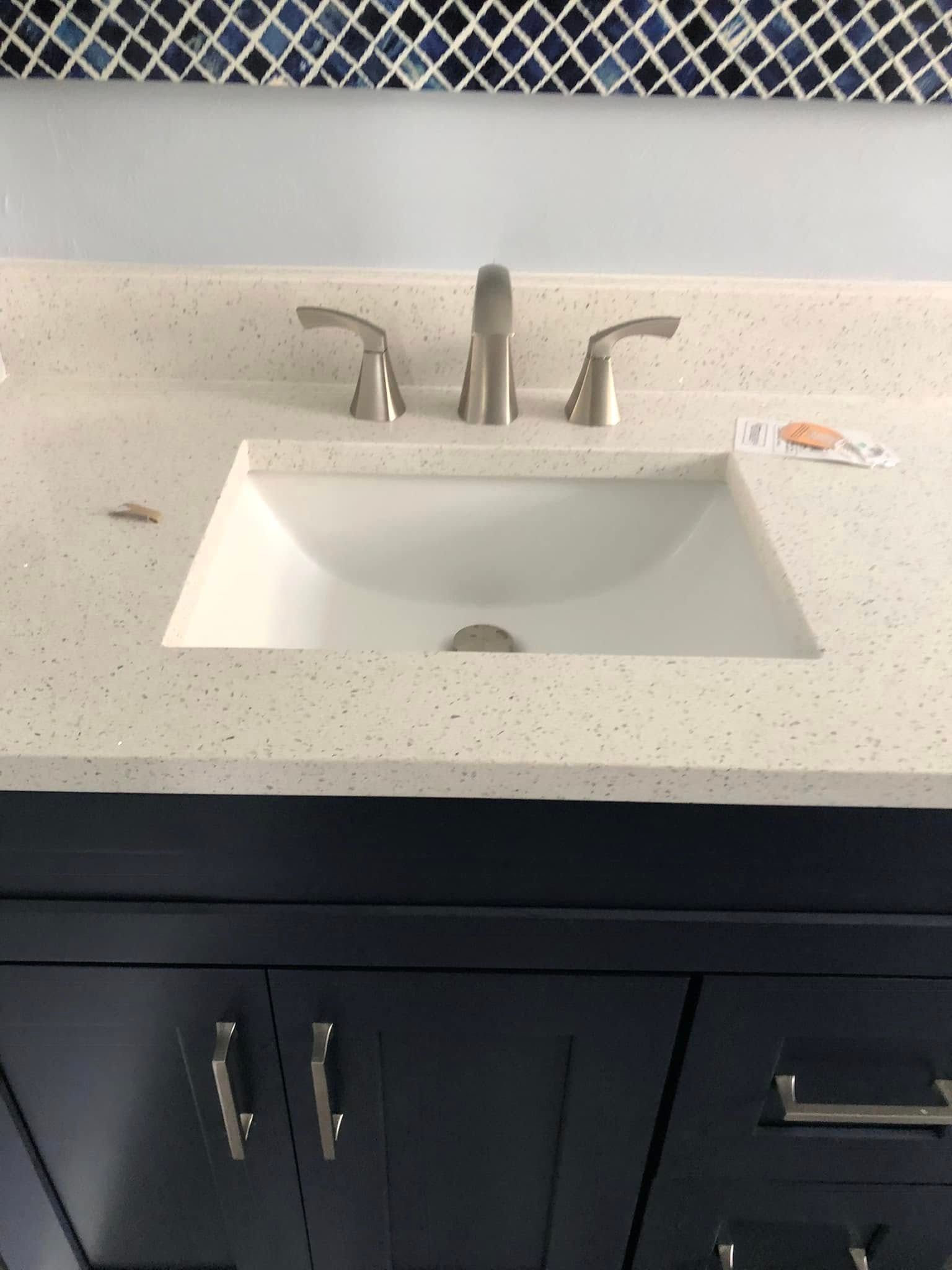 Bathroom vanity with white sink and countertop, chrome faucet, and dark cabinet below.