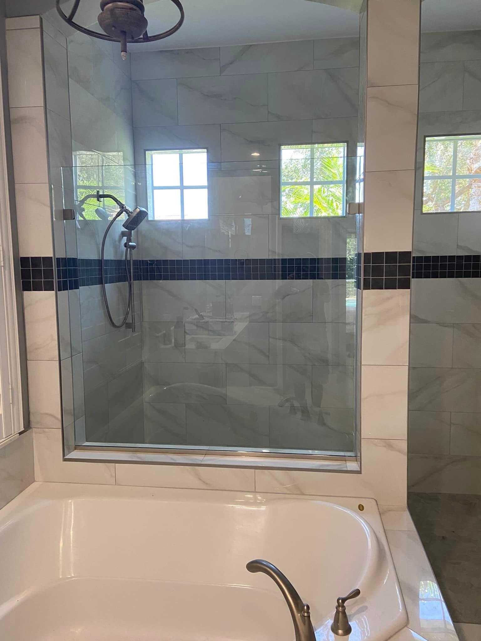 Bathroom with a glass shower enclosure, bathtub, and wall mirror above a sink.