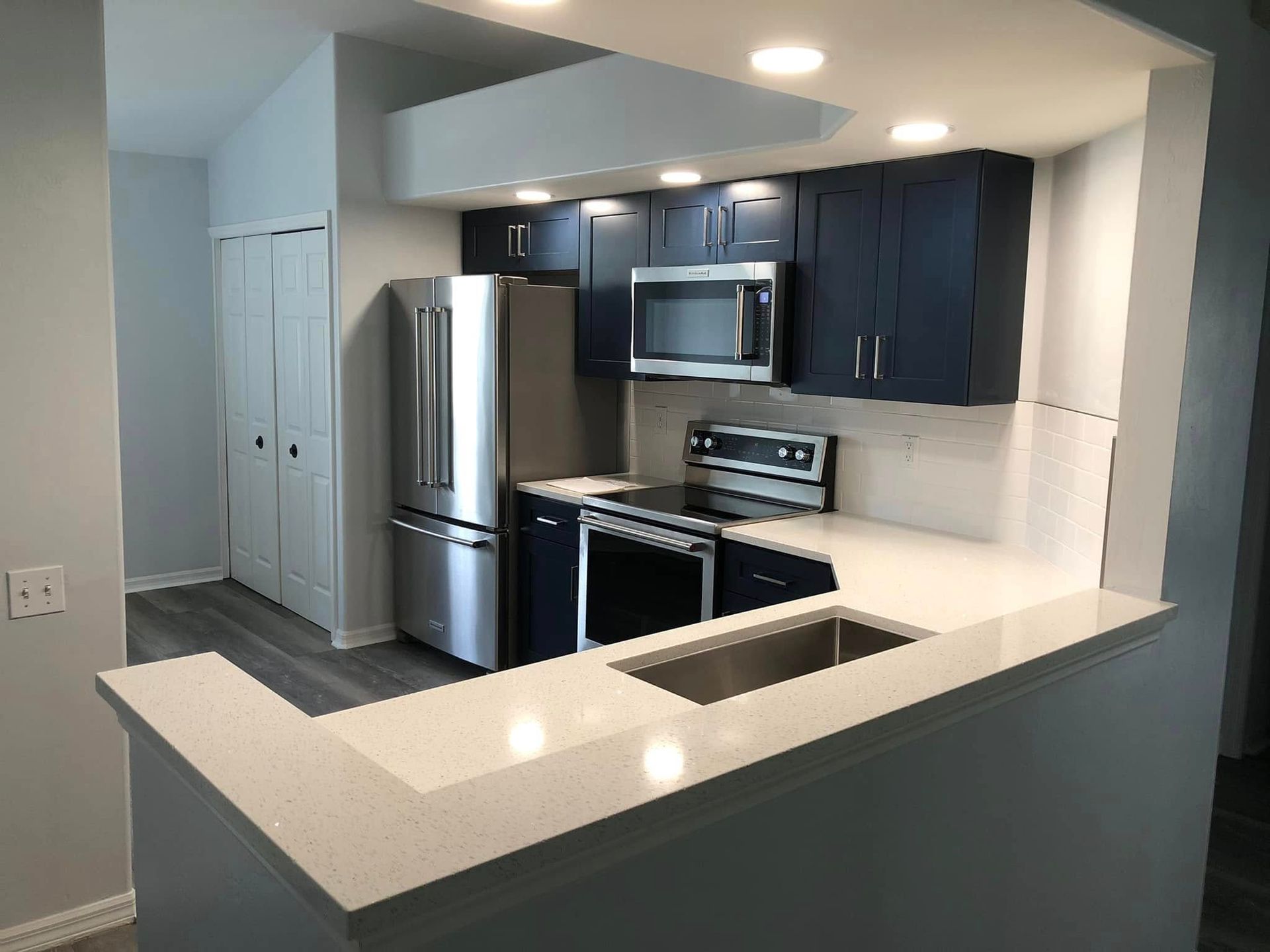 Modern kitchen with dark cabinets, stainless steel appliances, and a white breakfast bar