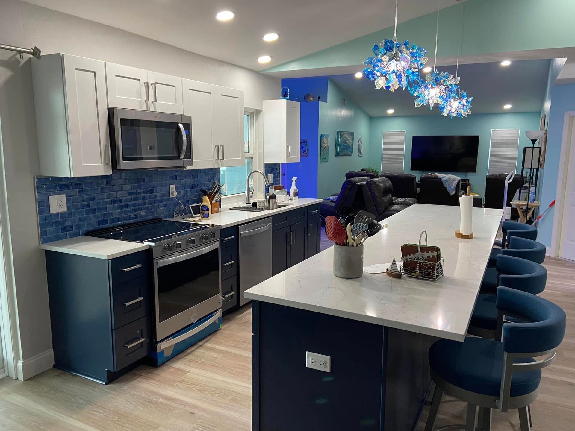 Modern kitchen with gray cabinets, blue backsplash, island seating, and pendant lights