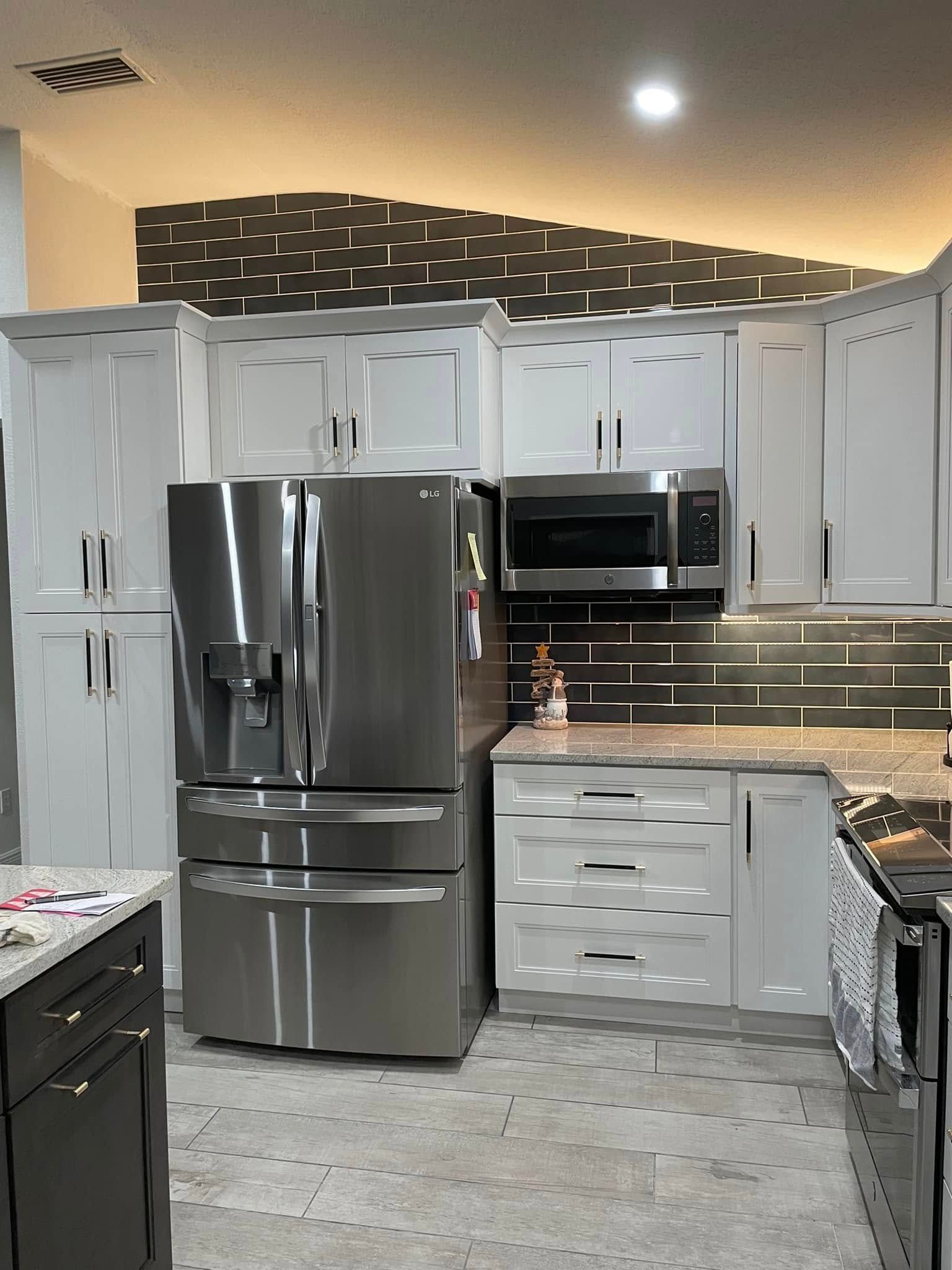 Modern kitchen with white cabinets, stainless steel appliances, and gray tile backsplash