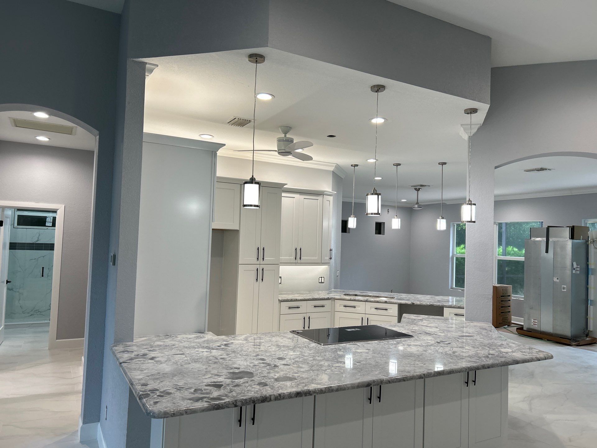 Modern kitchen with gray cabinets, marble island, pendant lights, and stainless steel appliances