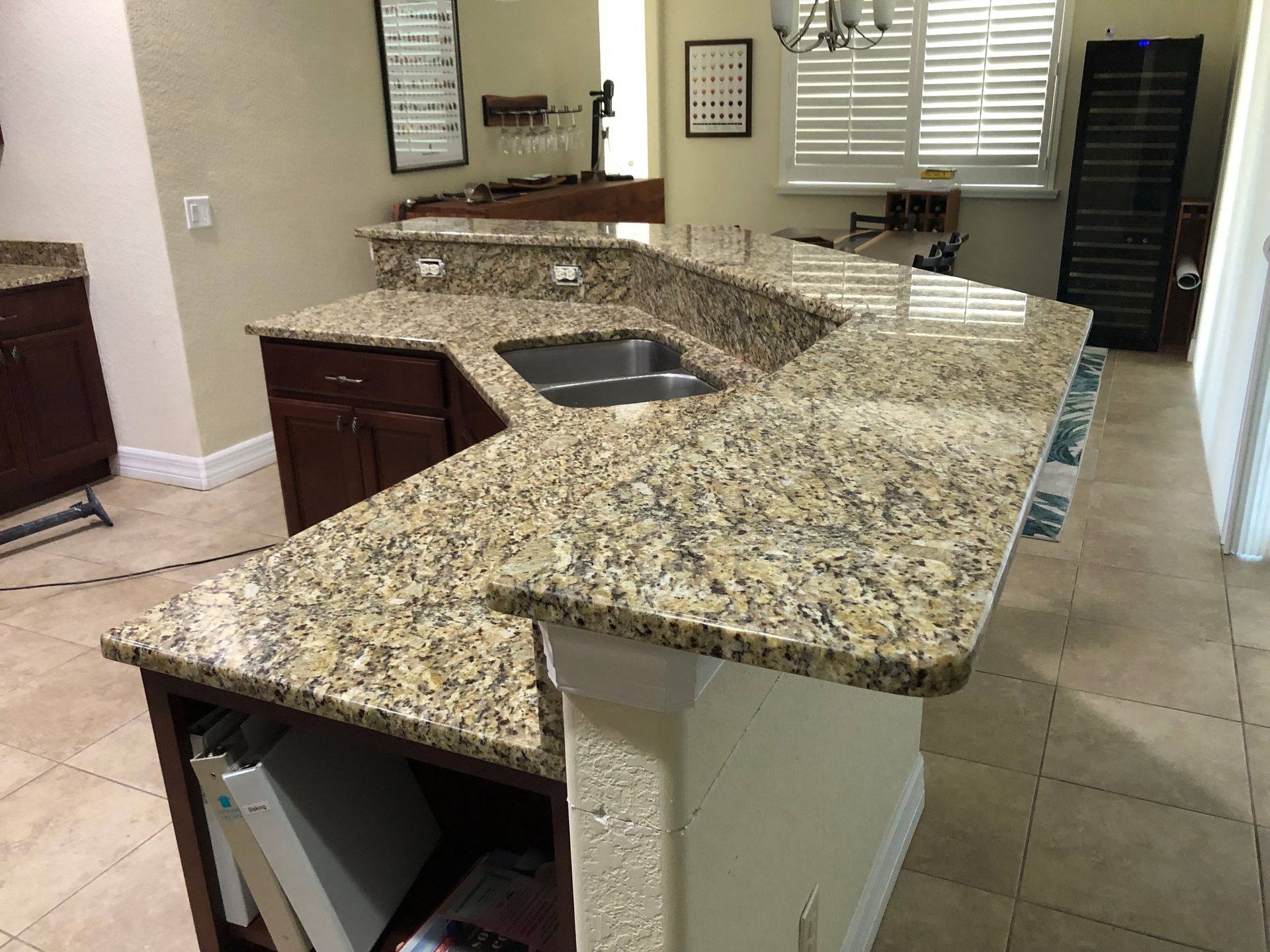 Kitchen island with granite countertop and built-in sink in a tiled kitchen.