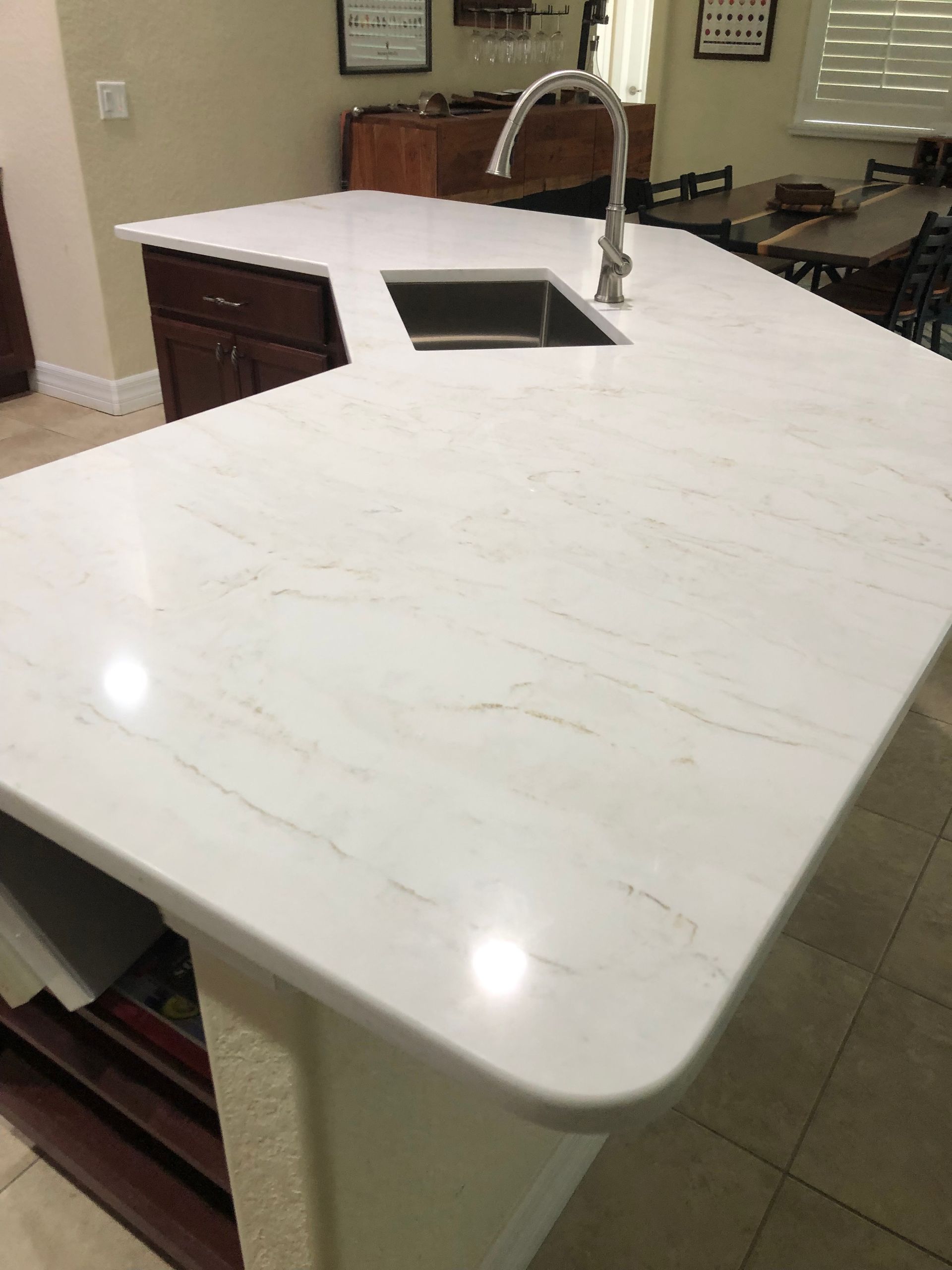Kitchen island with white countertop, built-in sink, and faucet in a modern kitchen.