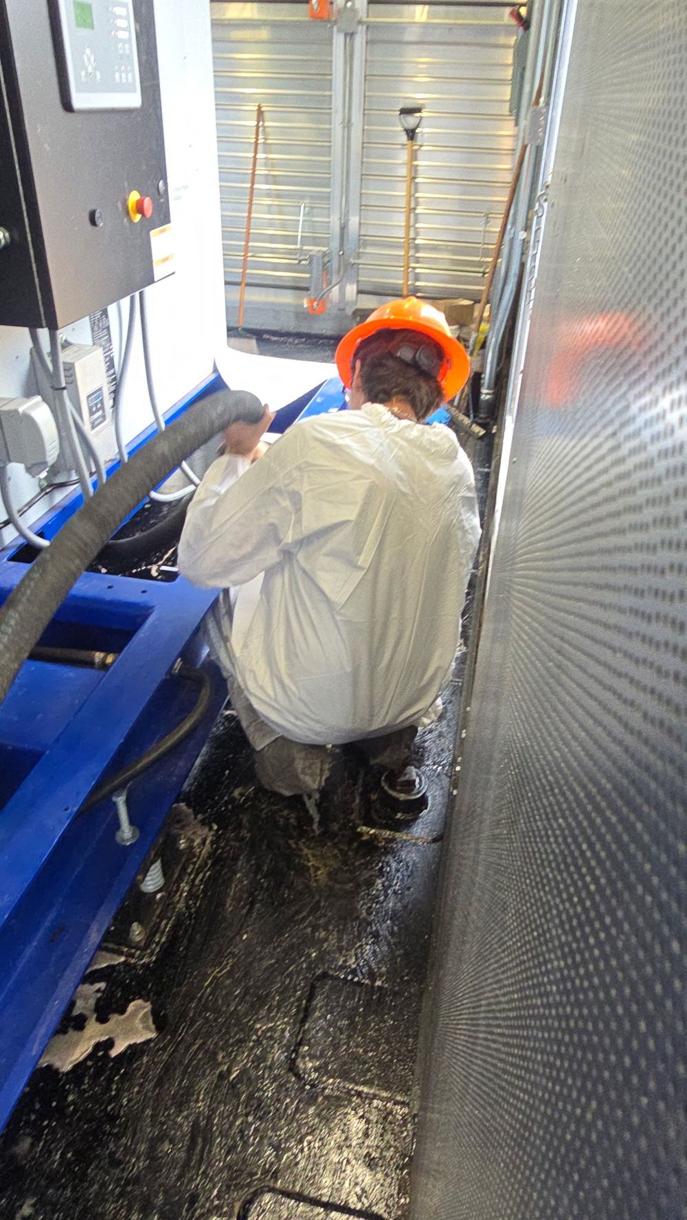 Trained SMR Rapid Response technician in a protective suit decontaminating industrial equipment