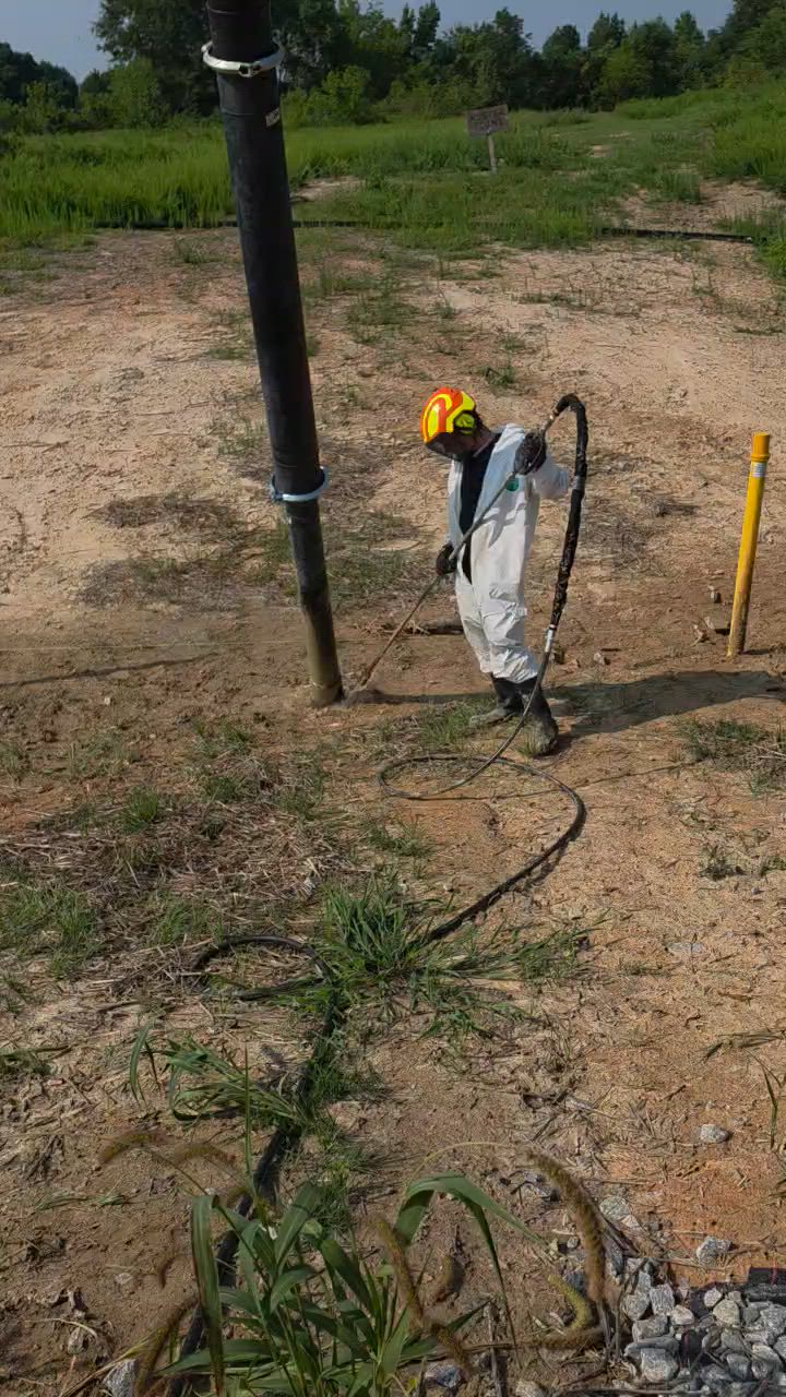 Technician in a protective suit running a hydro excavation dig at an industrial facility