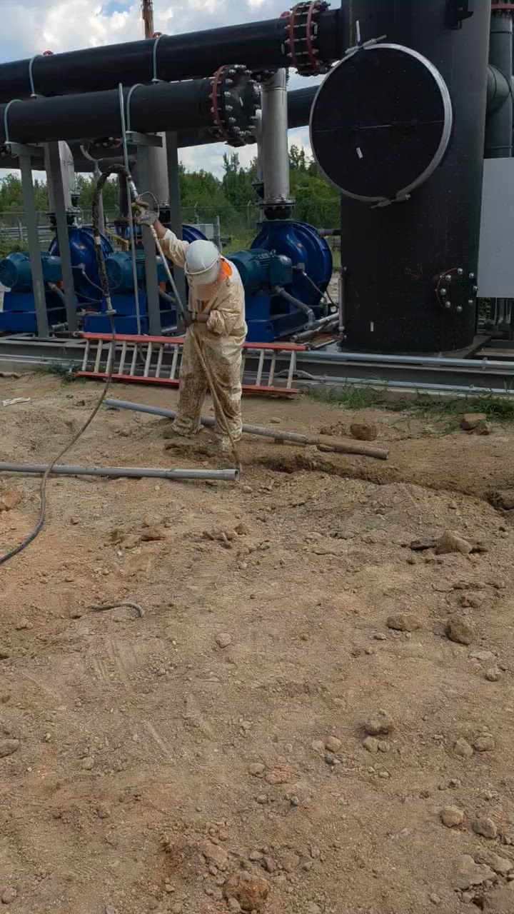 Technician performing non-destructive hydro excavation around buried utilities at an industrial site