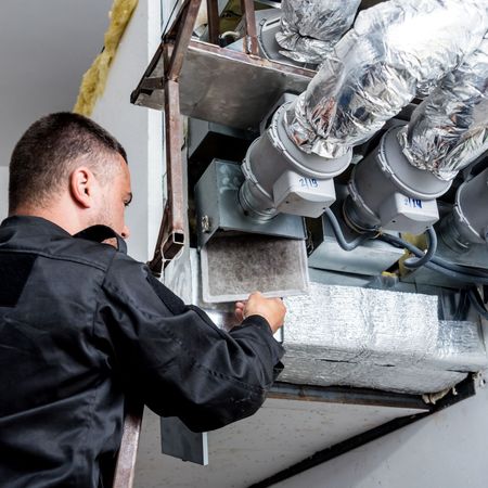 Dunn Right HVAC LLC | a man is working on a ventilation system in a building.