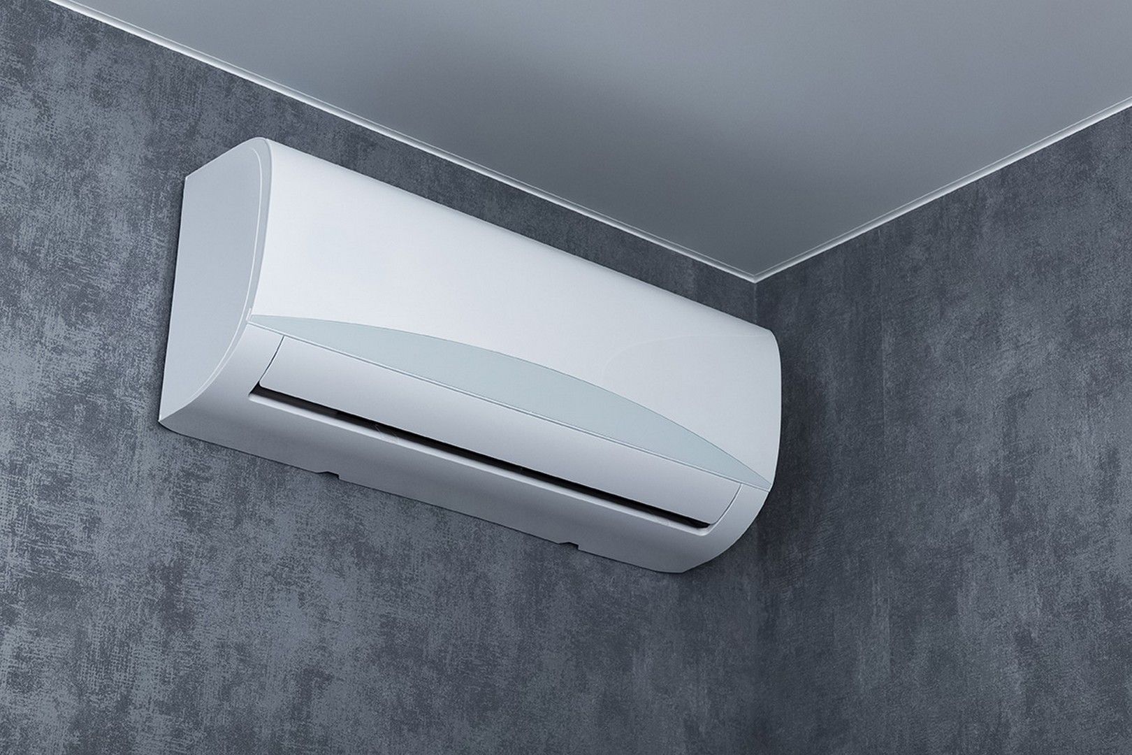 Condizionatore d'aria bianco montato su una parete grigia testurizzata vicino all'angolo del soffitto.