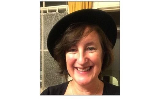 Pianodocent Heleen Verleur uit Amsterdam met een zwarte hoed staat binnen, vlakbij een deur.