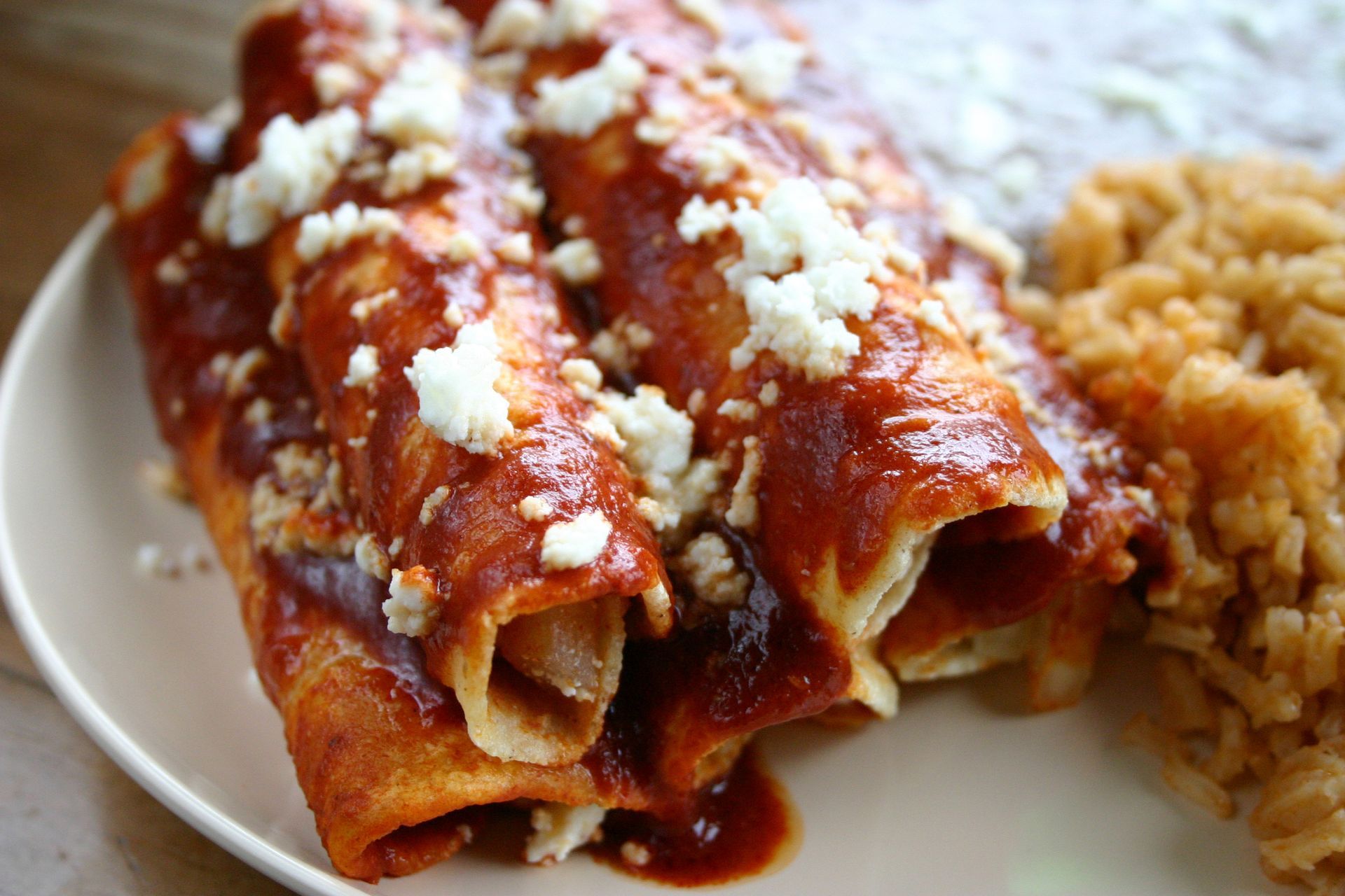 A white plate topped with enchiladas and rice.