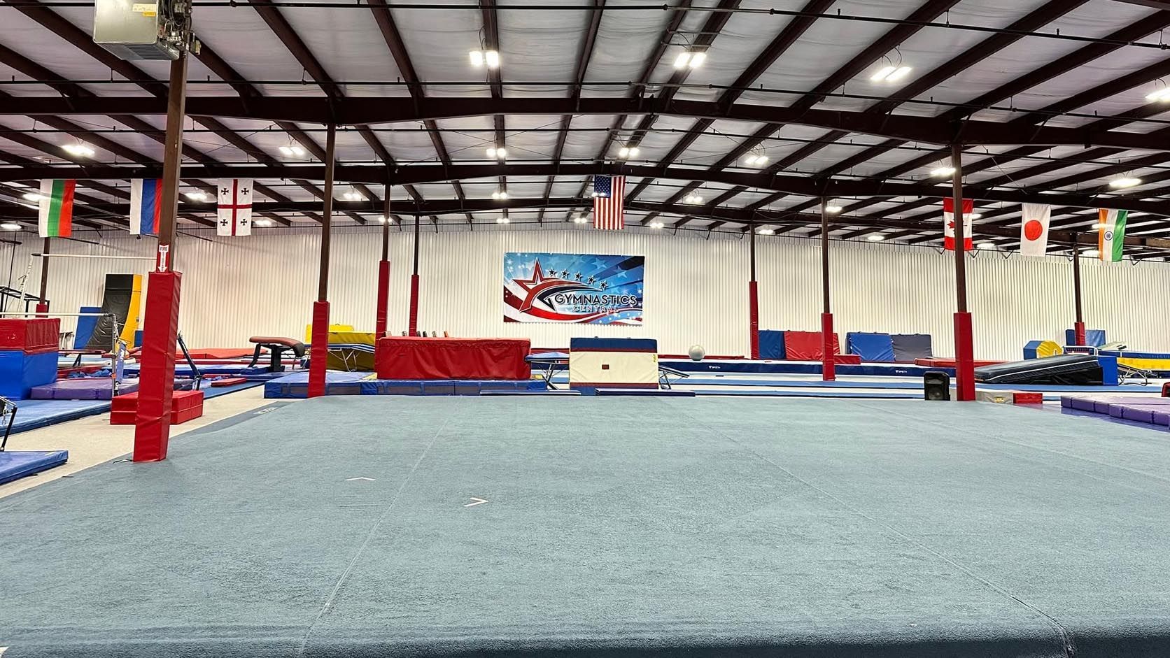 A young girl is sitting on a balance beam in a gym.