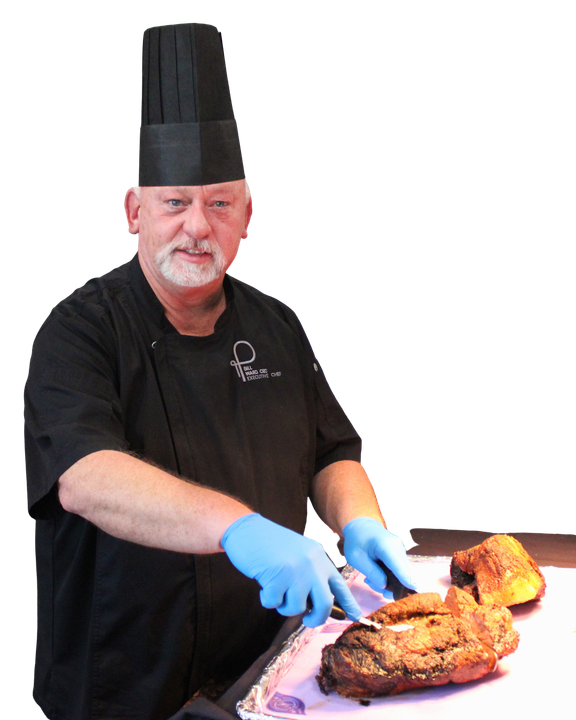 A chef in a black uniform and blue gloves carving a roasted piece of meat.