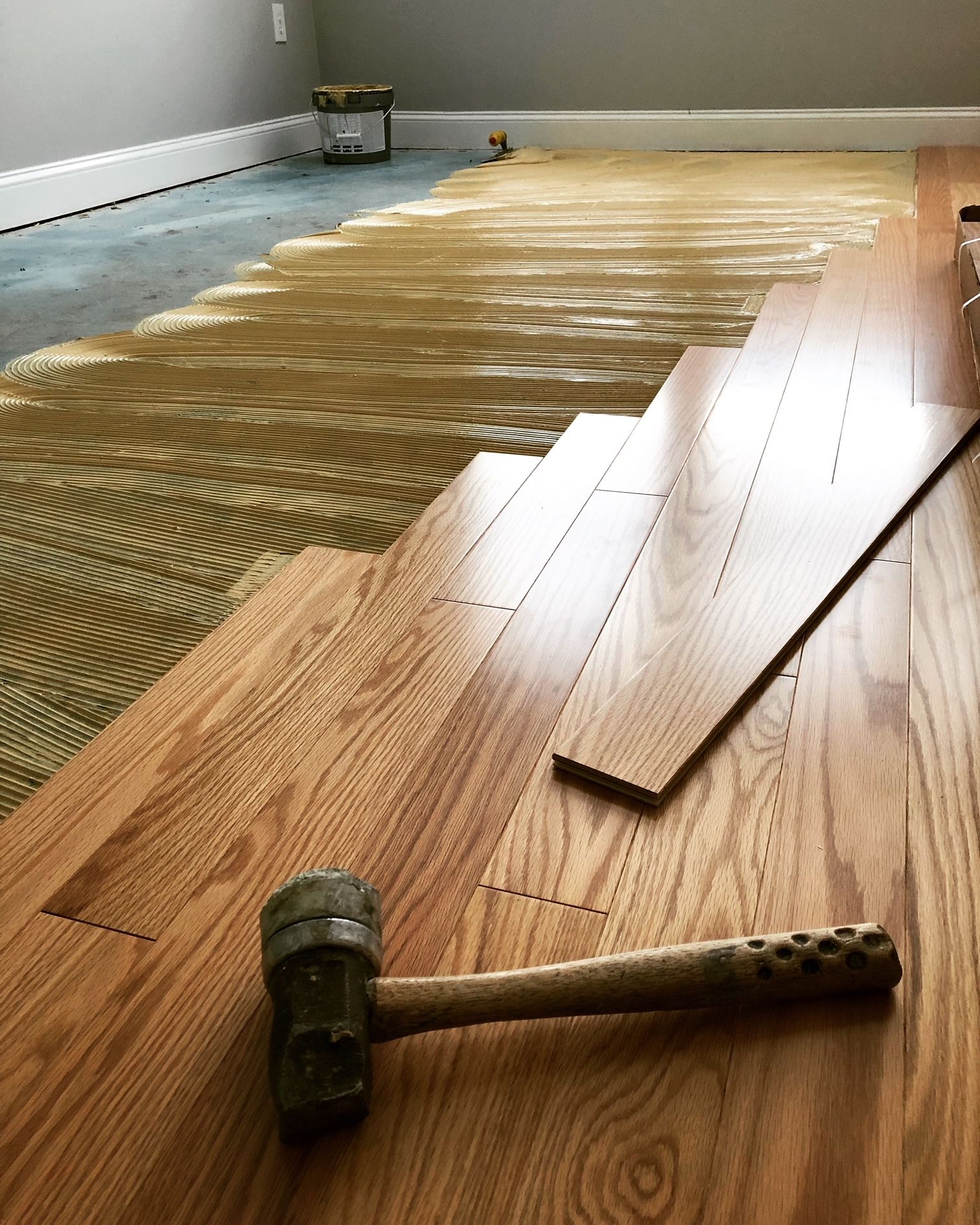 A hammer is sitting on top of a wooden floor.