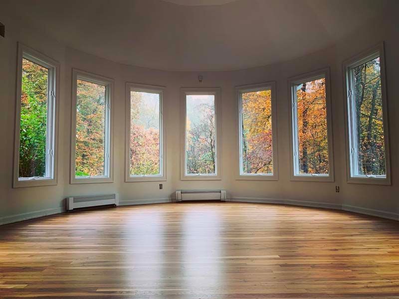An empty room with a lot of windows and a wooden floor.