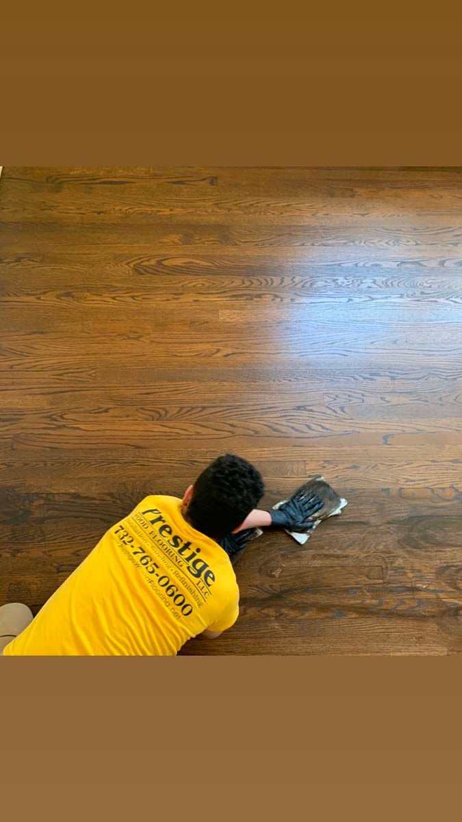 A man in a yellow shirt is cleaning a wooden floor.