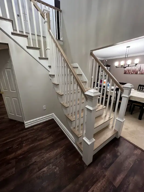 A staircase in a house with wooden steps and a white railing.