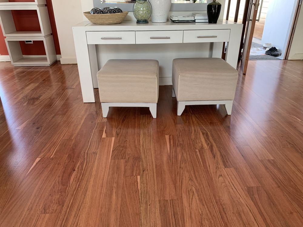 Dining area with white table, two beige ottomans, and wooden floor in bright room