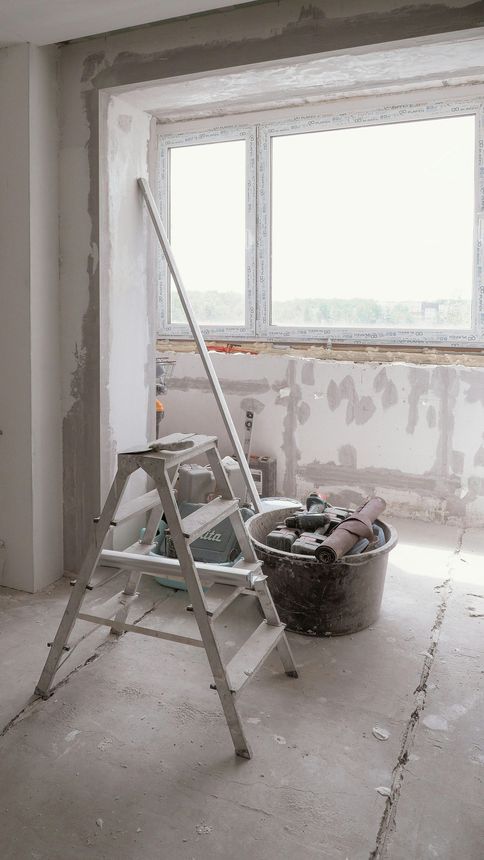 Renovation room with ladder, bucket of tools, and unfinished window wall