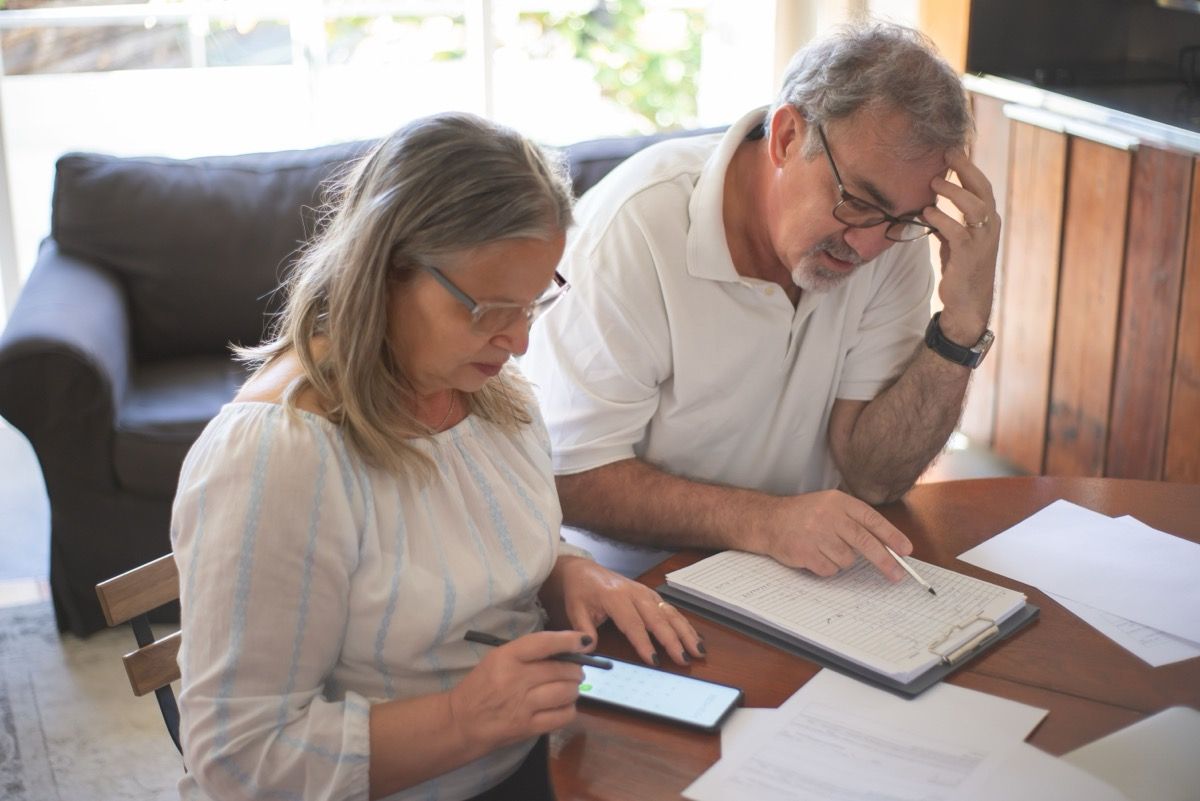 Two people at a table reviewing papers and a phone in a bright office.