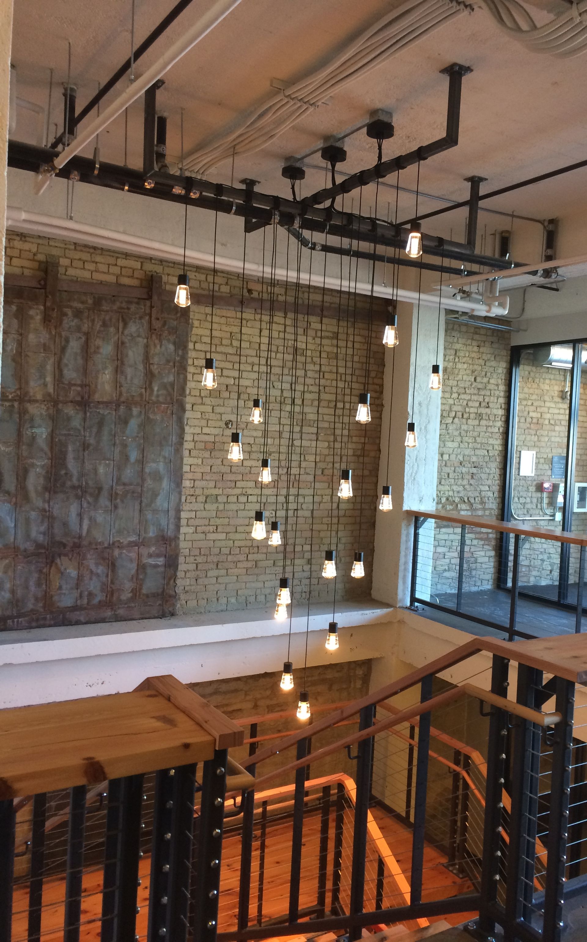 A staircase with a brick wall and lots of lights hanging from the ceiling.