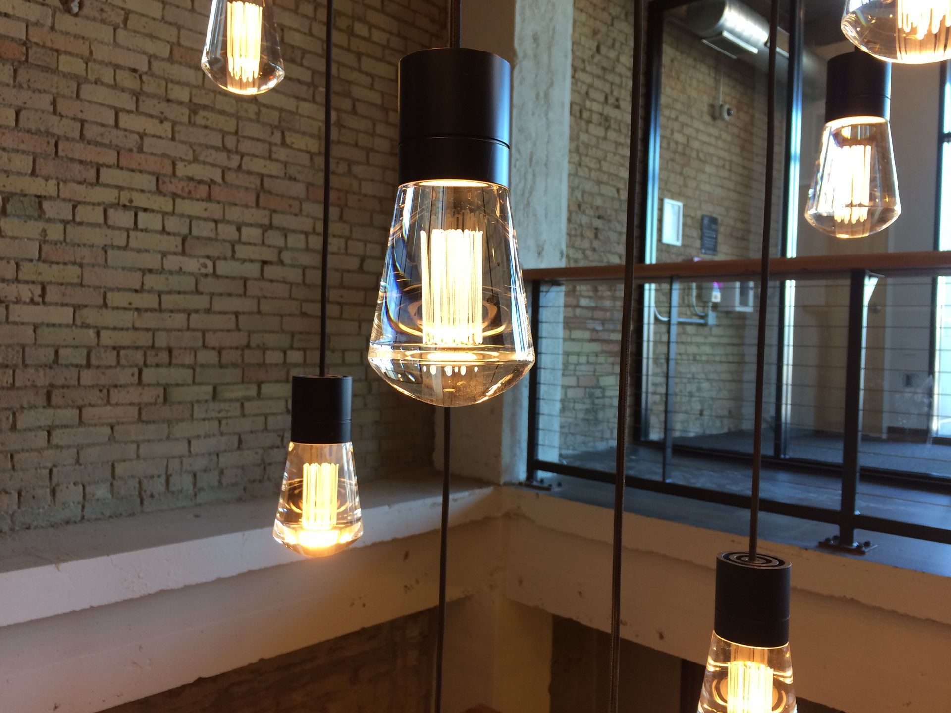 A bunch of light bulbs hanging from the ceiling in front of a brick wall