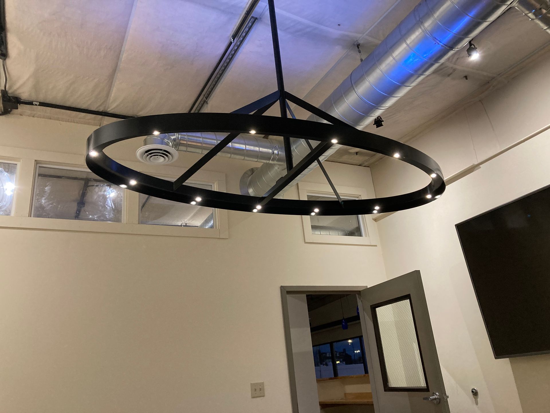A large black chandelier is hanging from the ceiling in a room