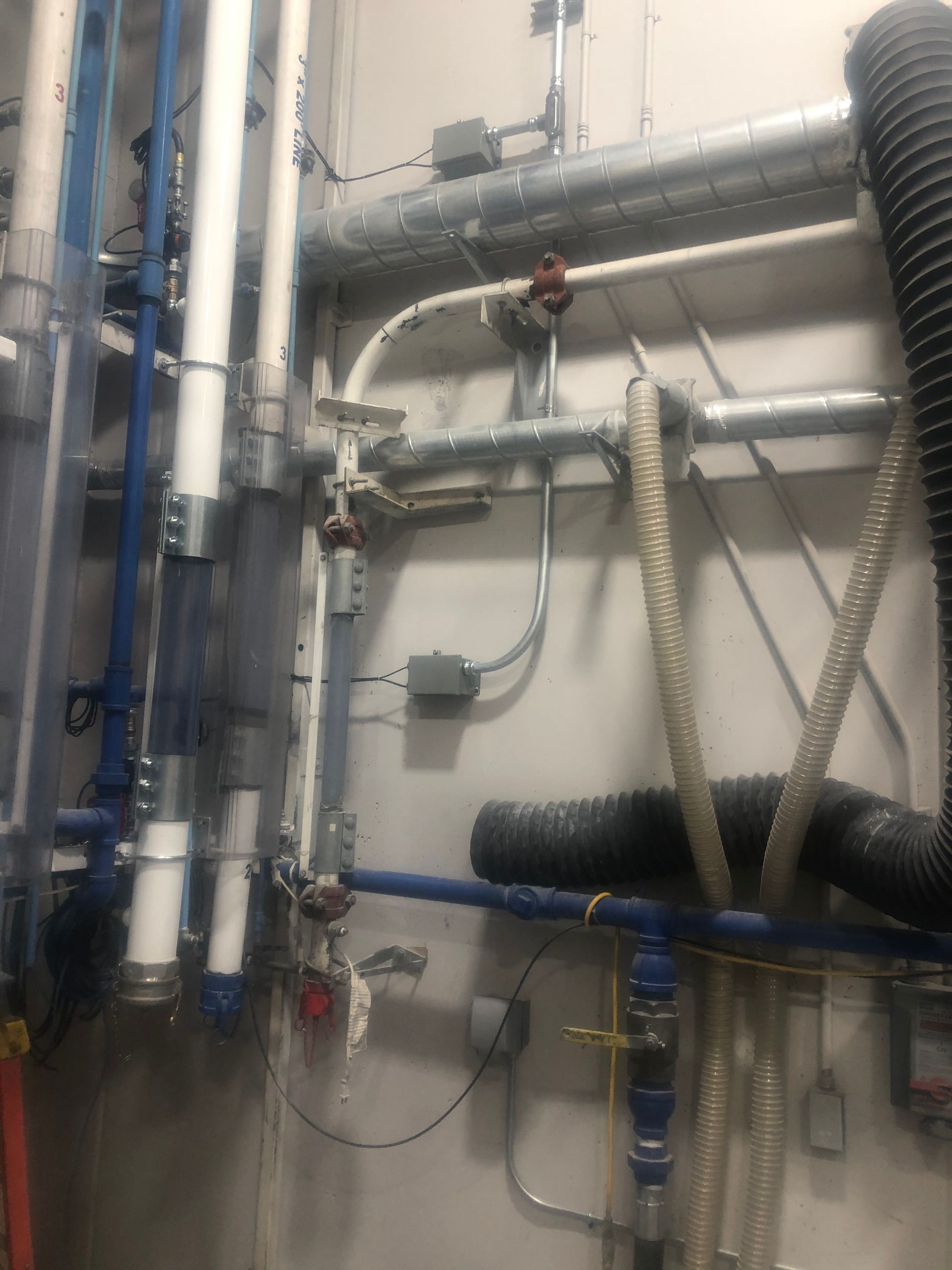 A room with a lot of pipes and wires on the wall.