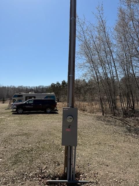 A rv is parked in a field next to a power box