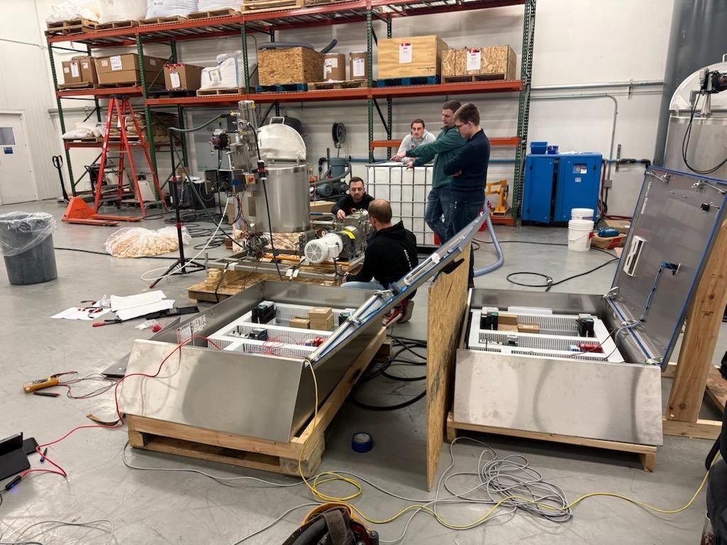 A group of people are working on a machine in a warehouse.