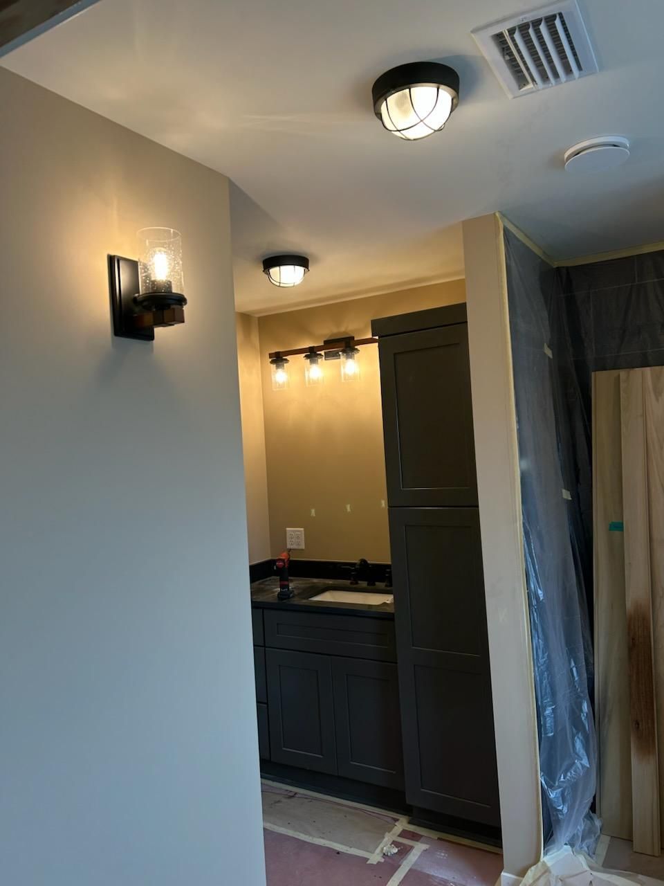 A bathroom with a sink , cabinets , and a ceiling light.