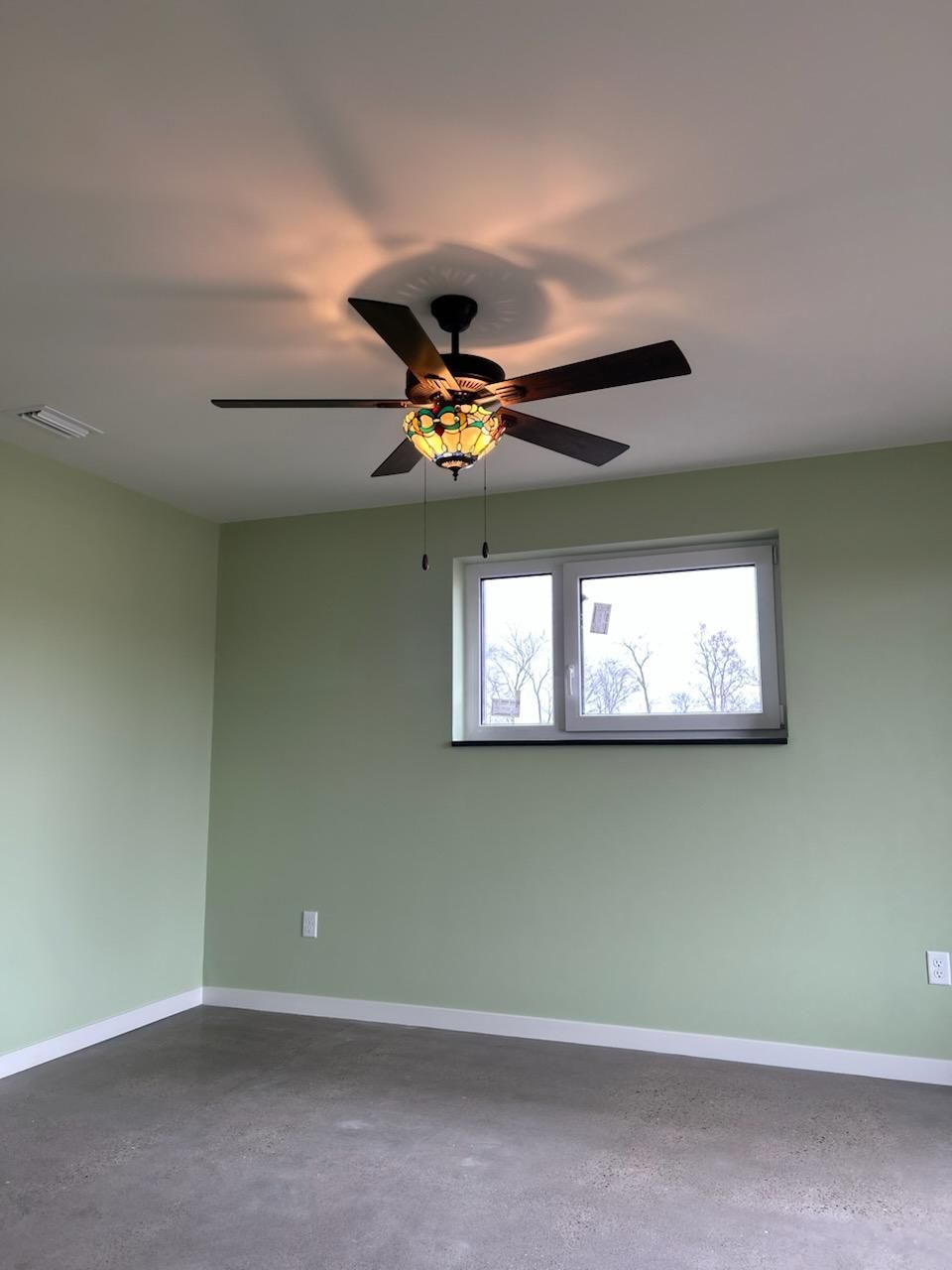 An empty room with a ceiling fan and a window