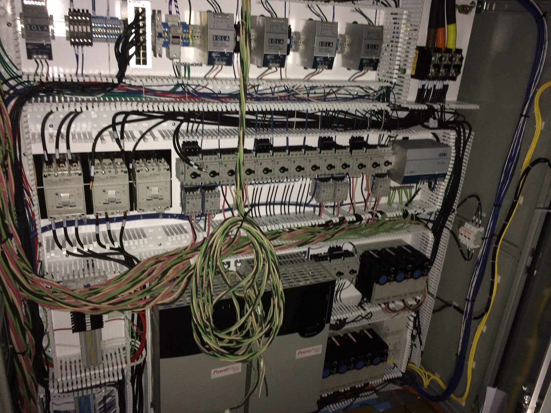 A large electrical panel with a lot of wires hanging from it