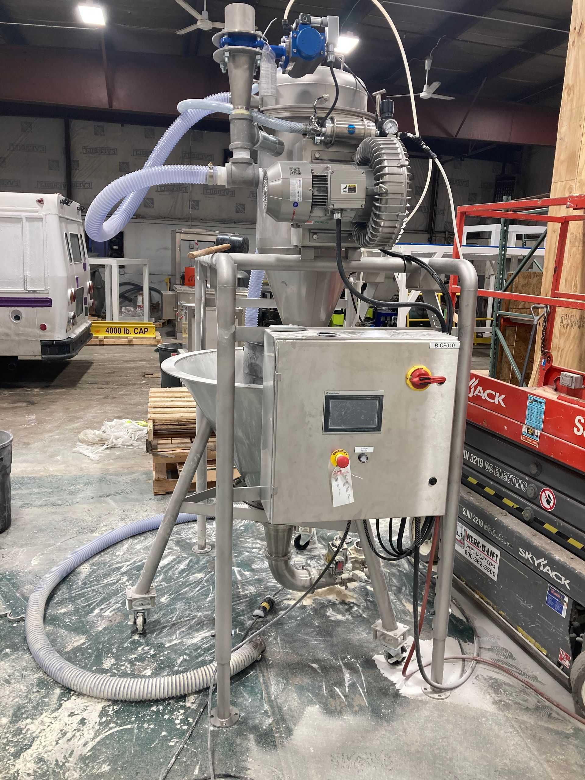 A machine is sitting in a warehouse with a hose attached to it.